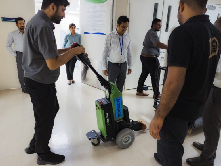 Hospital staff member driving the MOVEXX TT1500-T electric tug, lithium battery visible, at a private hospital in Dubai