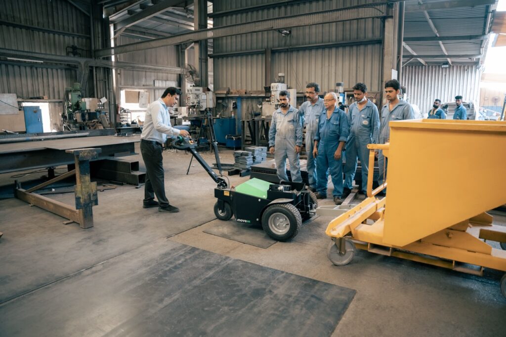 ADW Machinery demonstrating the MOVEXX TT2500-S-AT electric tug towing a tipping skip to the production team at a glass factory in Ras Al Khaimah